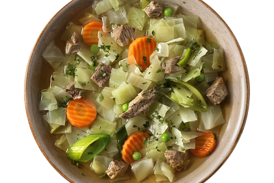 Eine Schüssel Pichelsteiner Eintopf mit Karotten, Weißkohl, Erbsen und Kräutern von Hofmanns Shop.
