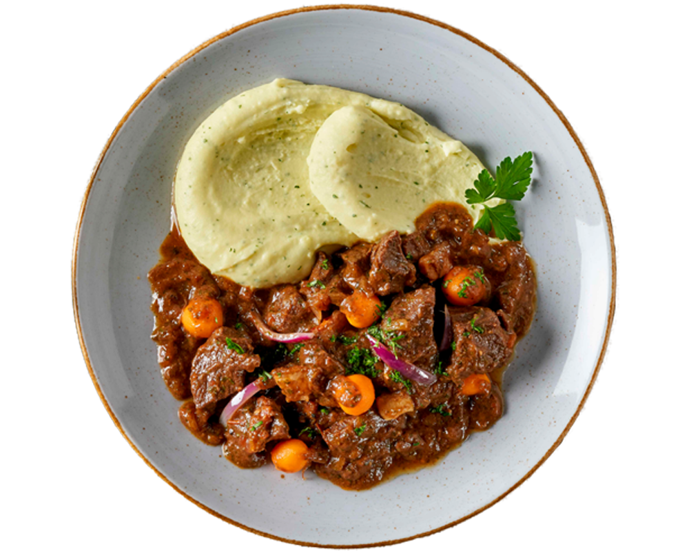 Ein Teller mit Boeuf à la Bourguignon von Hofmanns Shop, cremigem Kartoffelstampf, einem Eintopf aus zartem Rindfleisch mit Karotten und Zwiebeln, alles garniert mit Petersilie und liebevoll mit Rotwein geschmort für mehr Geschmackstiefe.